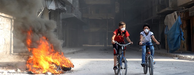 ALEPPO, SYRIA - AUGUST 4: Syrian children ride bikes as Syrian opponents burn tires to block the ground visibility of the war crafts belonging to the Russian Army and Assad regime forces at an opposition controlled neighborhood in Aleppo, Syria on August 4, 2016.  Ibrahim Ebu Leys / Anadolu Agency
